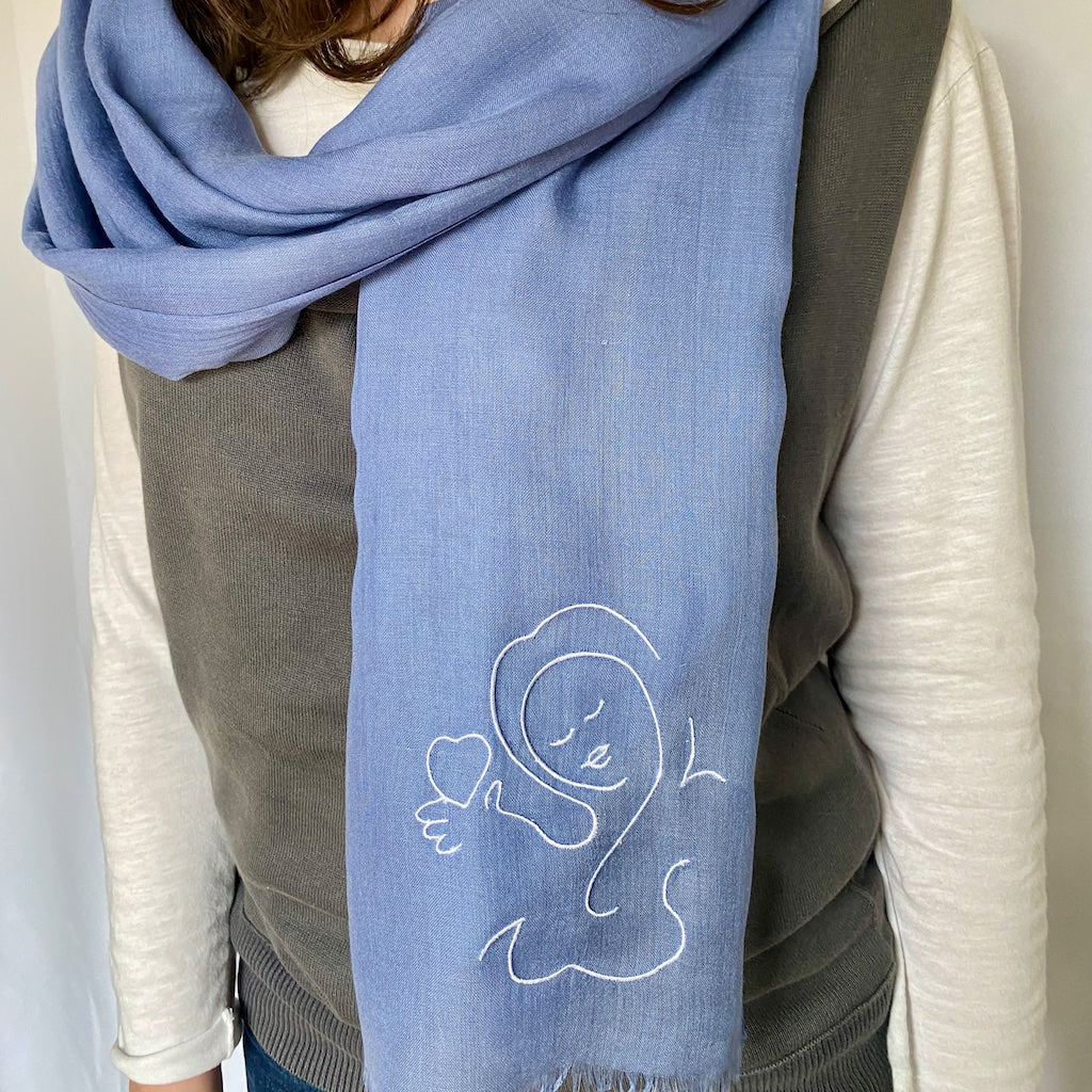 Muze blue lightweight scarf in modal and silk on model displaying embroidery of muze love original artistic drawing on one side