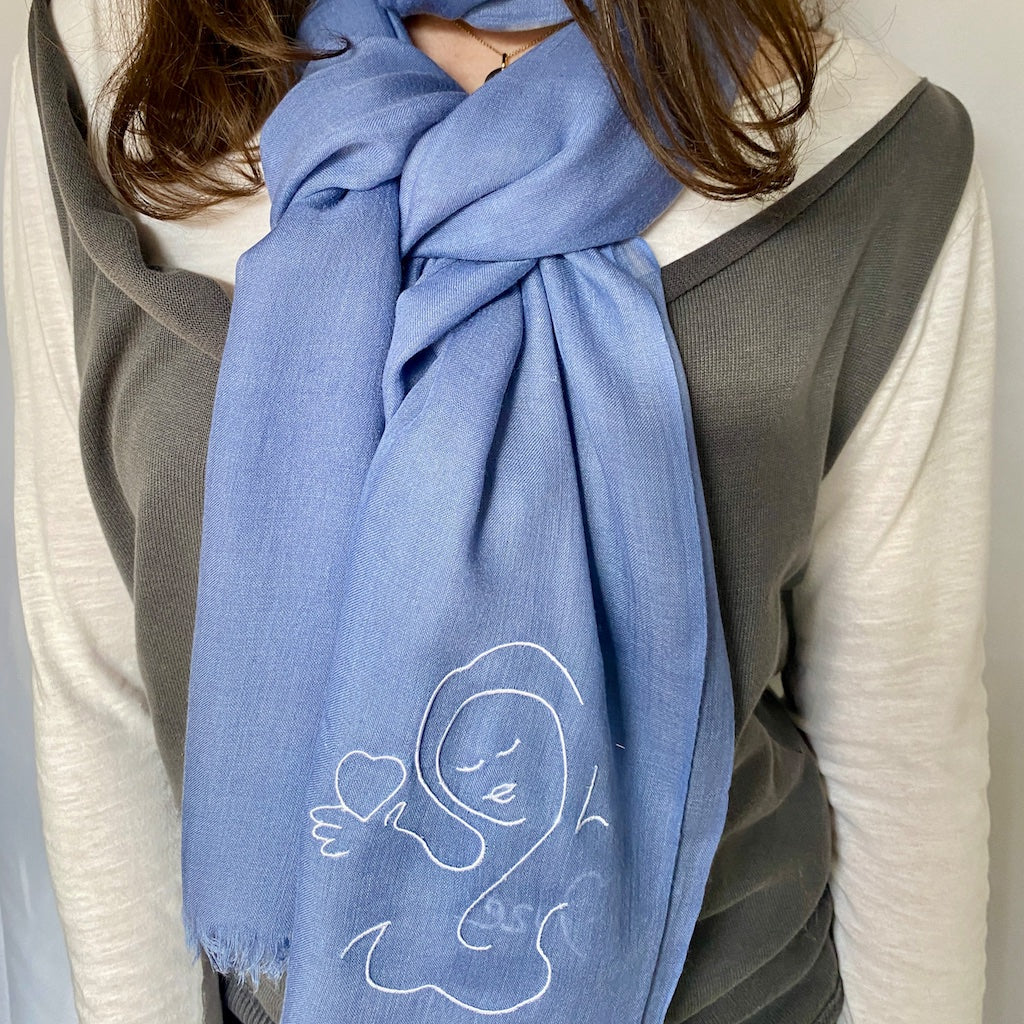 Muze blue lightweight scarf in modal and silk on model displaying embroidery of muze love original artistic drawing on one side