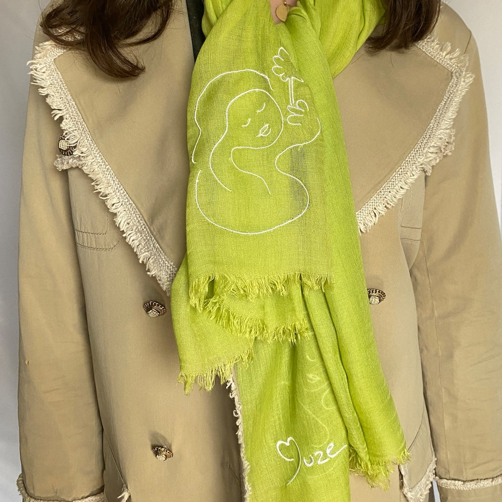 Muze green lightweight scarf in modal and silk on model displaying embroidery of muze peace and muze logo original artistic drawings