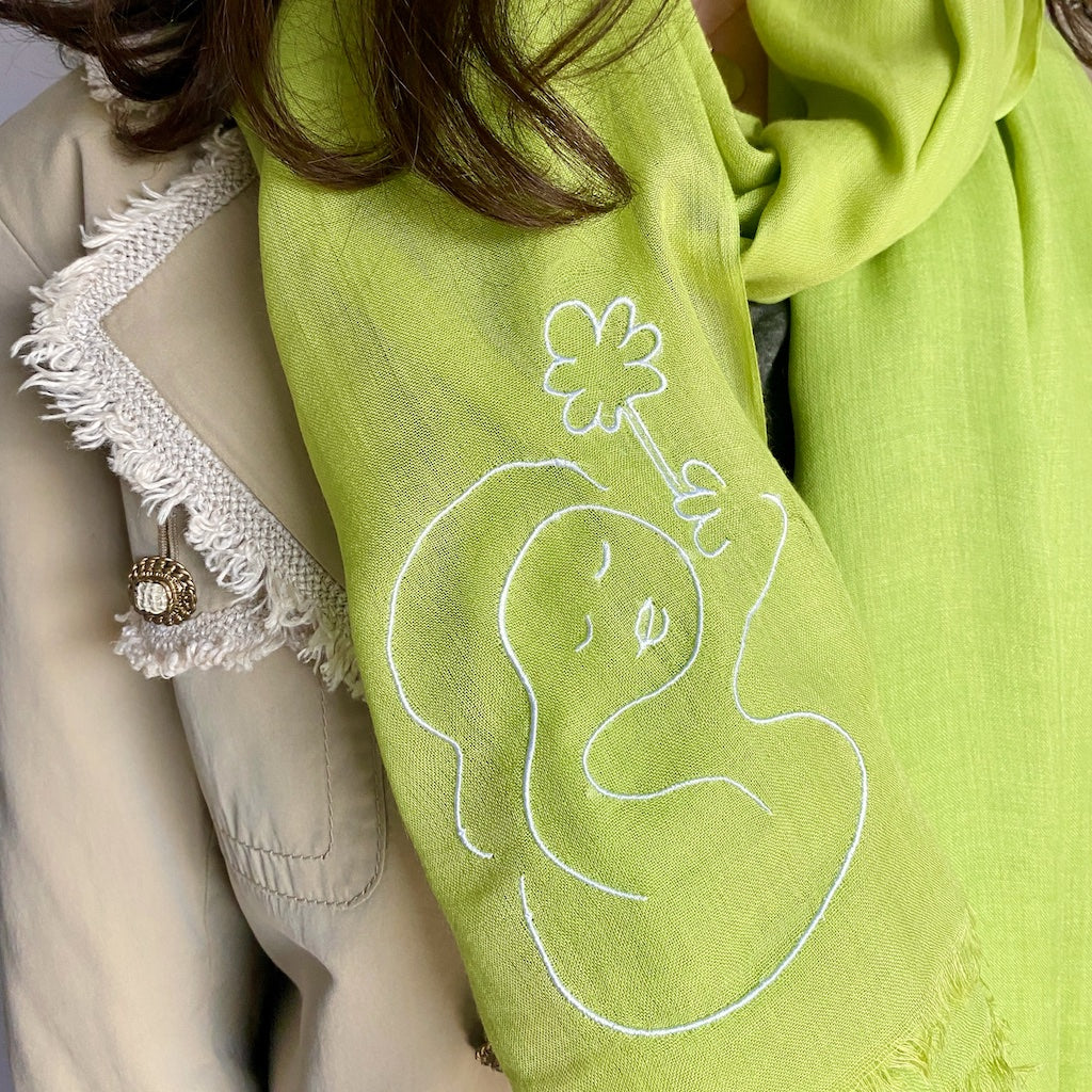 Muze green lightweight scarf in modal and silk on model displaying embroidery of muze peace original artistic drawing
