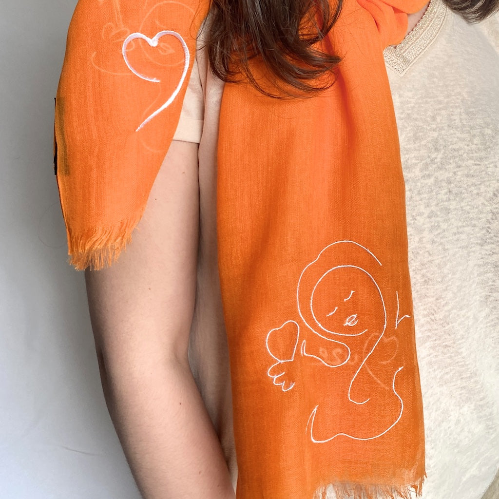 Muze orange lightweight scarf in modal and silk on model displaying embroidery of muze love and heart original artistic drawing