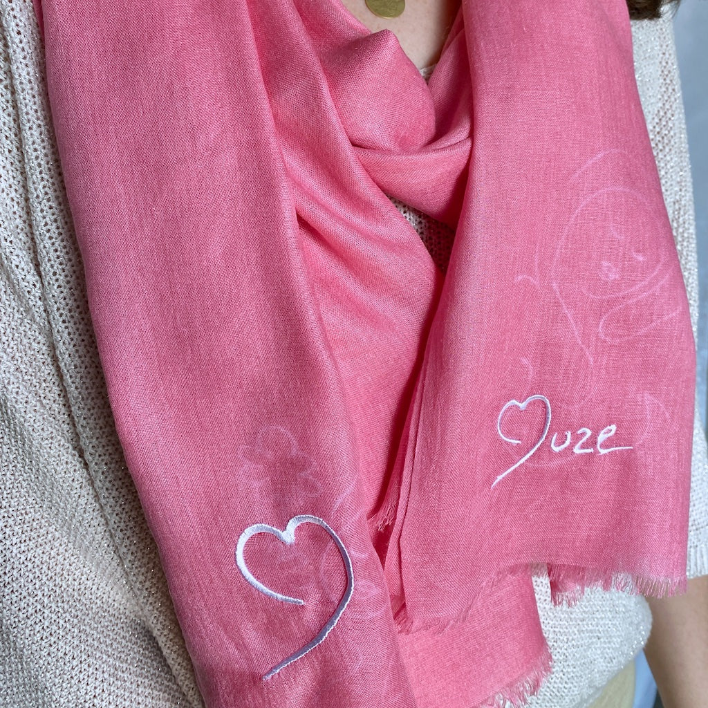 Muze pink lightweight scarf in modal and silk on model displaying embroidery of a heart shape and muze logo