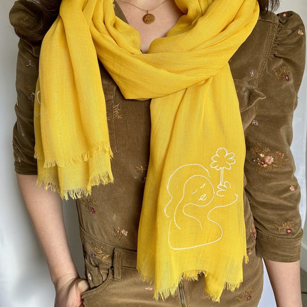 Muze yellow lightweight scarf in modal and silk on model displaying embroidery of muze peace original artistic drawing