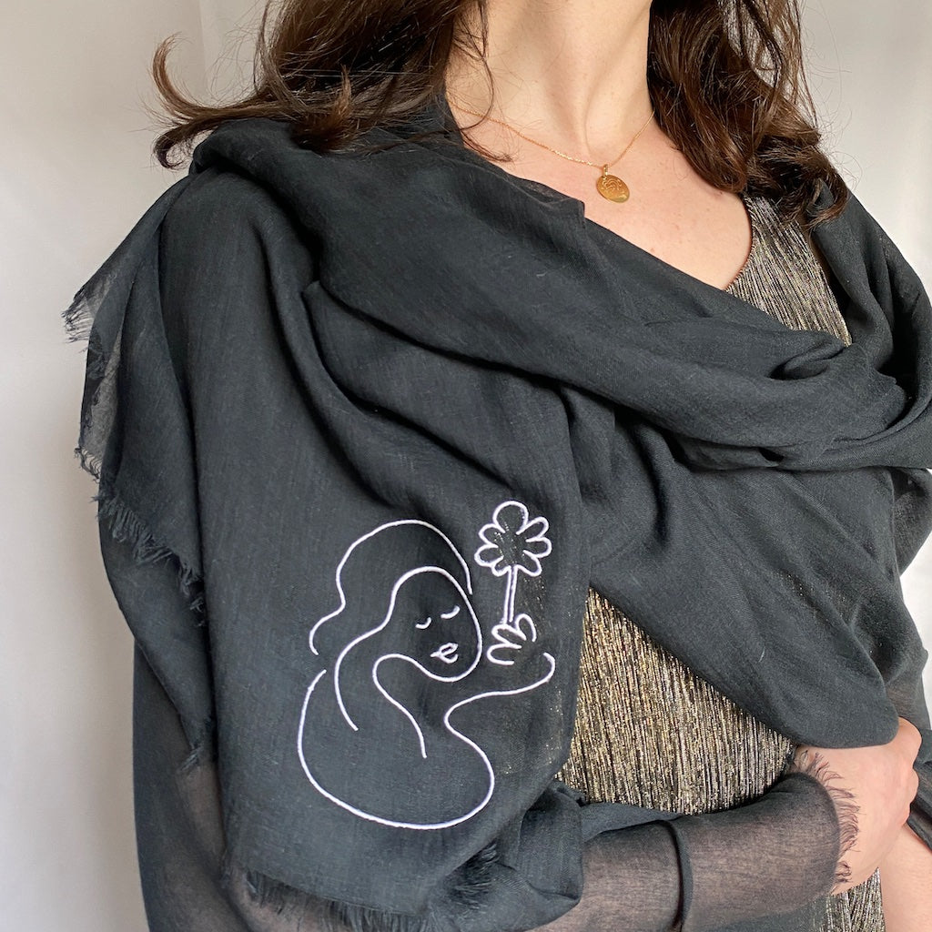 Muze black lightweight scarf in modal and silk on model displaying embroidery of muze peace original artistic drawing