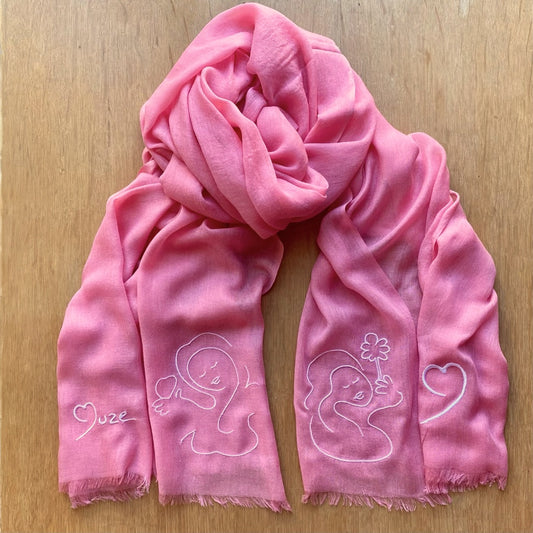 Muze pink lightweight scarf in modal and silk on model displaying embroidery of  Muze peace and love drawing